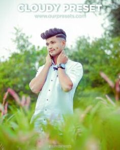 a man standing in the grass talking on his cell phone while holding his hand to his ear