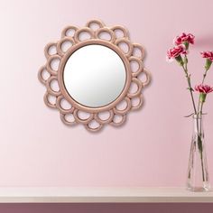 there is a vase with flowers and a mirror on the wall next to pink walls