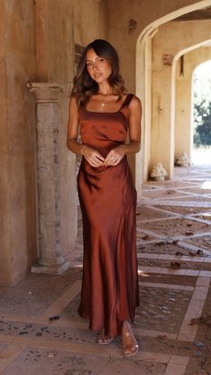 a woman standing in an archway wearing a brown dress