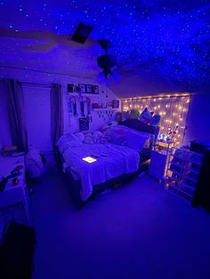 a bedroom is lit up with purple lights and stars on the ceiling, along with a bed