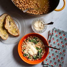 an orange bowl filled with beans and spinach next to two slices of toasted bread