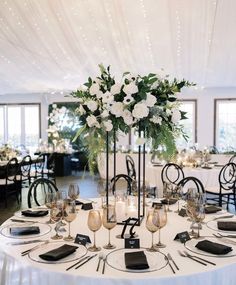 a table set with white flowers and place settings for an elegant dinner or reception party