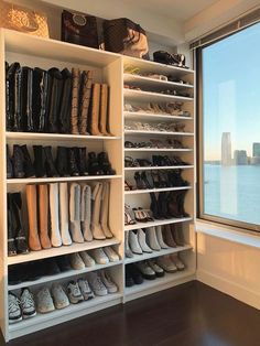 a closet with many pairs of shoes on shelves next to a window overlooking the water