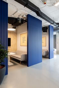 an office with blue partitions in the center and white couches on either side