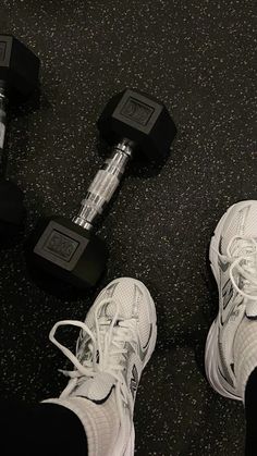 a pair of feet with white sneakers and black dumbbells