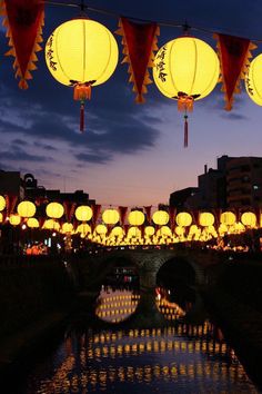 lanterns are hanging over a river at night