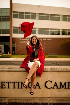 a woman sitting on top of a sign with a red flag in the air above her head