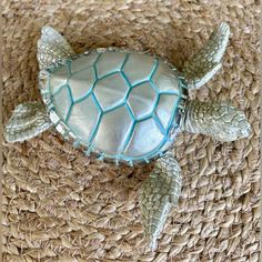 a small sea turtle sitting on top of a piece of woven material next to a cell phone