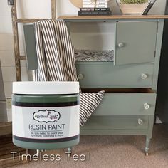 a green painted dresser with a striped towel on it's side and a white jar of paint sitting next to it