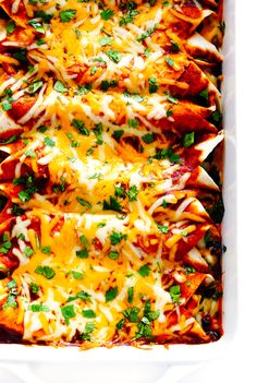 a white casserole dish filled with cheesy chicken enchiladas