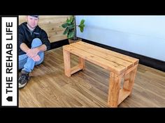 a man sitting on the floor next to a wooden bench