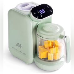 a green blender filled with cubes of fruit next to a timer on the side