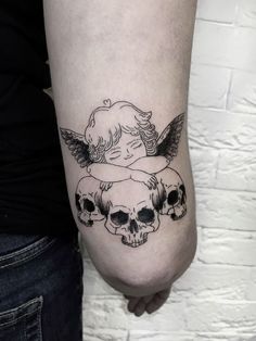 a woman's arm with three skulls and an angel tattoo on the back of it