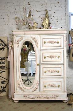 a white dresser with a mirror on top of it in front of a bicycle and mannequins