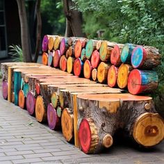 several wooden logs are lined up on the side of a brick sidewalk in front of some trees