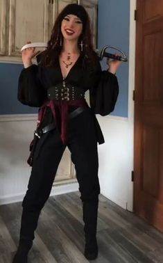 a woman dressed in pirate costume holding two wrenches and posing for the camera with one hand on her hip