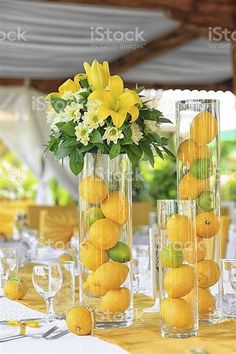 the table is set with lemons and flowers in vases