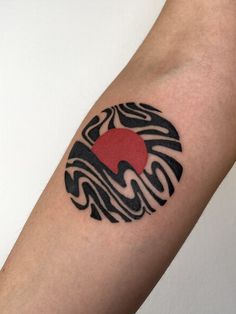 a tattoo on the arm of a person with waves and a red sun in the center