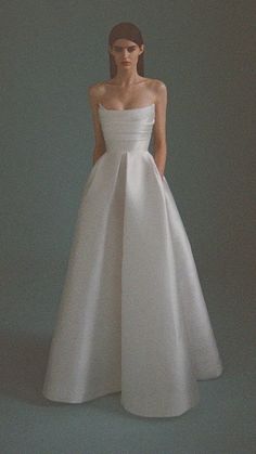 a woman in a white dress standing against a gray background