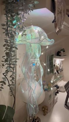 a glass jellyfish sculpture hanging from the ceiling in a room with plants and other decorations