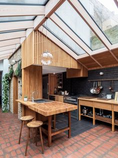 an open kitchen and dining area in a house with brick flooring, wooden walls and ceiling