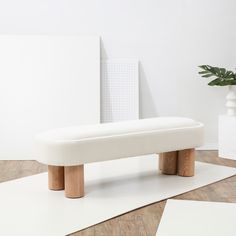 a white bench sitting on top of a wooden floor next to a potted plant