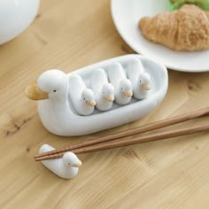 small white birds in a boat with chopsticks on a table next to some food