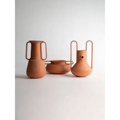 three vases and one bowl on a white surface with the handles extended to hold them