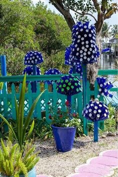 blue and white polka dot umbrellas in front of a green fence