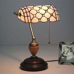 a lamp that is on top of a table next to a picture frame and an old photo