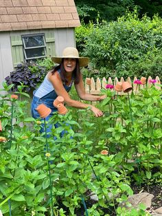 a woman in a hat is tending to her garden