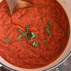 a pot filled with red sauce and garnish on top of a wooden table