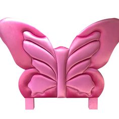 a pink butterfly shaped object sitting on top of a wooden stand in front of a white background