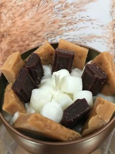 a bowl filled with marshmallows and chocolate on top of a marble table