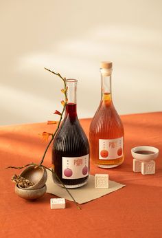 two bottles of wine sitting on top of a table next to an empty bowl and spoon