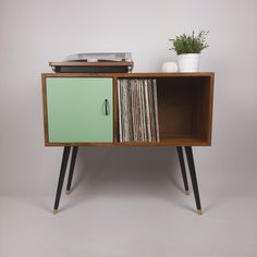 a record player sitting on top of a wooden cabinet next to a potted plant