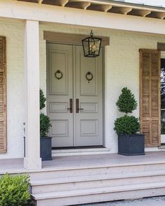 the front door of a white house with two planters