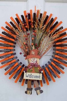 a wreath made out of carrots with a scarecrow on it and a welcome sign hanging from the front door