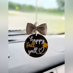 a happy fall y'all ornament hanging from the dashboard of a car