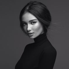 a black and white photo of a woman wearing a turtle neck top with her hair blowing in the wind