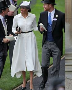 two men and a woman dressed in formal wear walking down the street with hats on