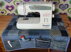 a sewing machine sitting on top of a pair of jeans in front of a colorful wall