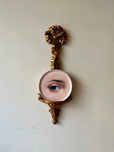 a mirror with an eye on it hanging on the wall next to a white wall