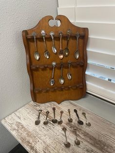 spoons are arranged on a wooden shelf in front of a window