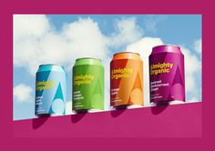 four cans of energy drink on top of a pink wall with clouds in the background