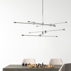 a modern chandelier hanging over a dining room table with chess pieces on it