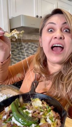 a woman is eating food from a frying pan