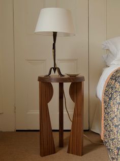 a wooden table with a lamp on it next to a bed