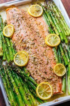 salmon and asparagus on a baking sheet with lemons