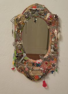 a mirror that is covered in many different things on the wall and hanging from it's sides